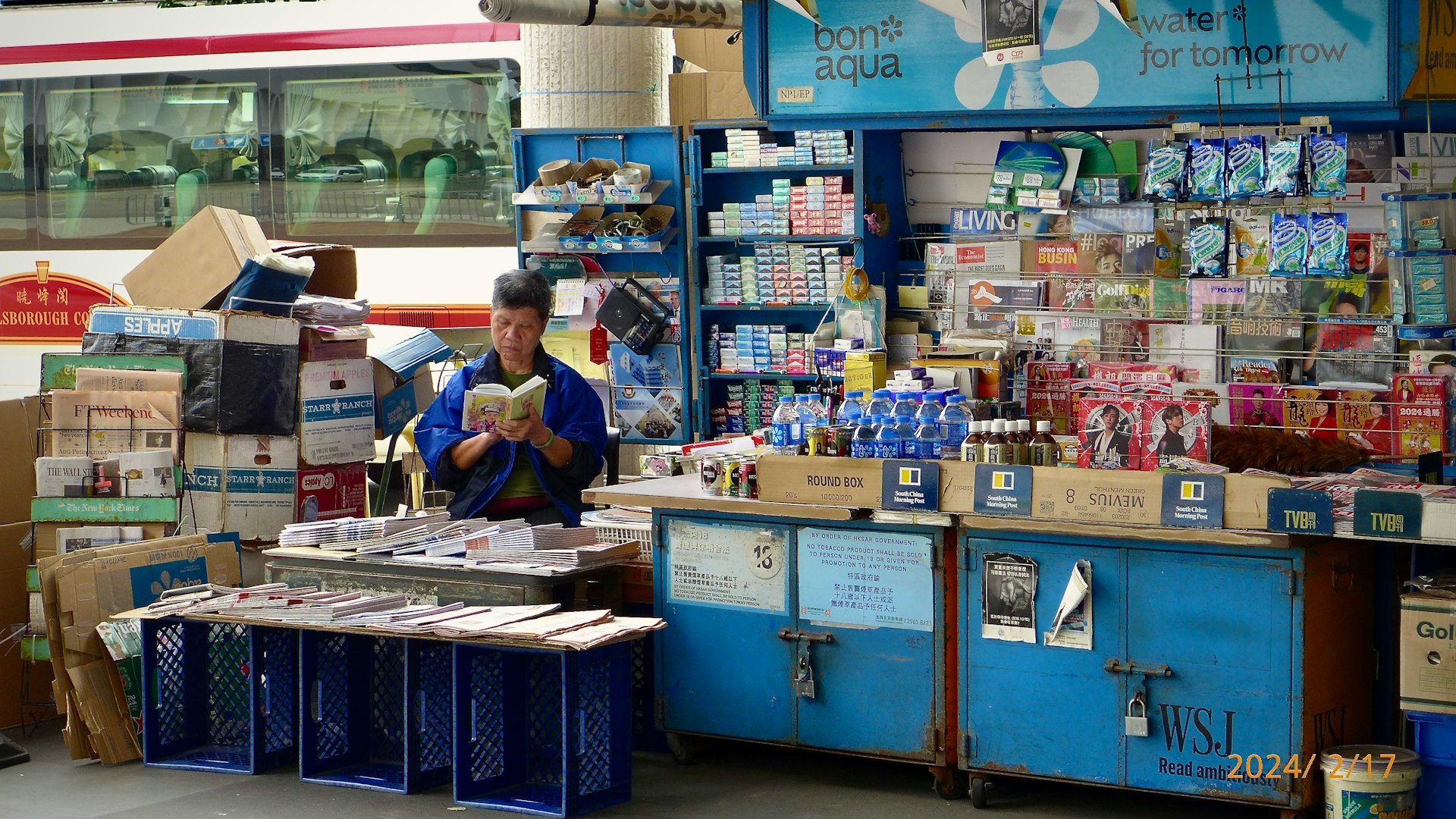 A man standing in front of a store filled with items
